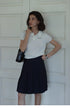 Pleated Chic Skirt navy blue high waist front view styled with white top, showcasing structured pleats and flattering silhouette
