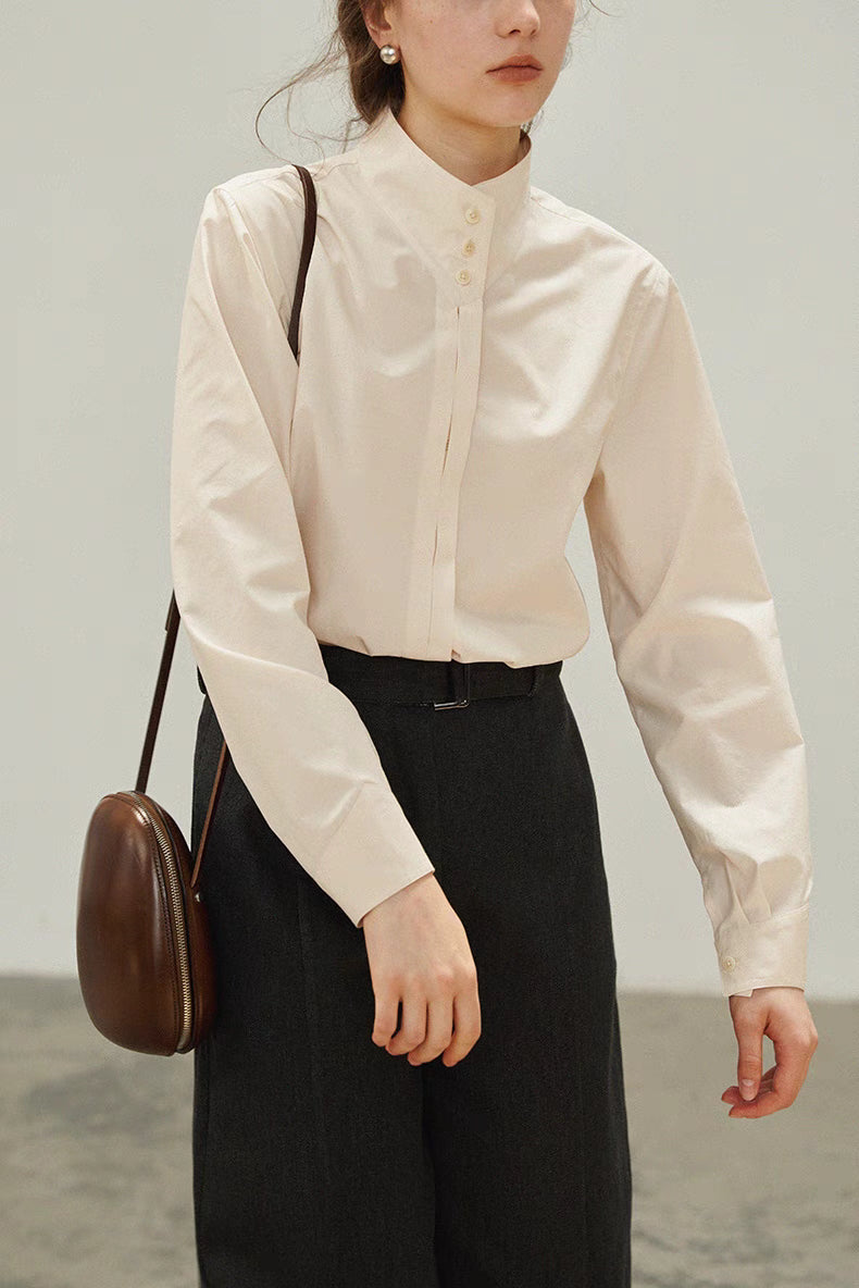 Close front view of Off-White stand-collar shirt featuring pleated placket detail, long sleeves, and styled with a brown crossbody bag for a refined everyday look