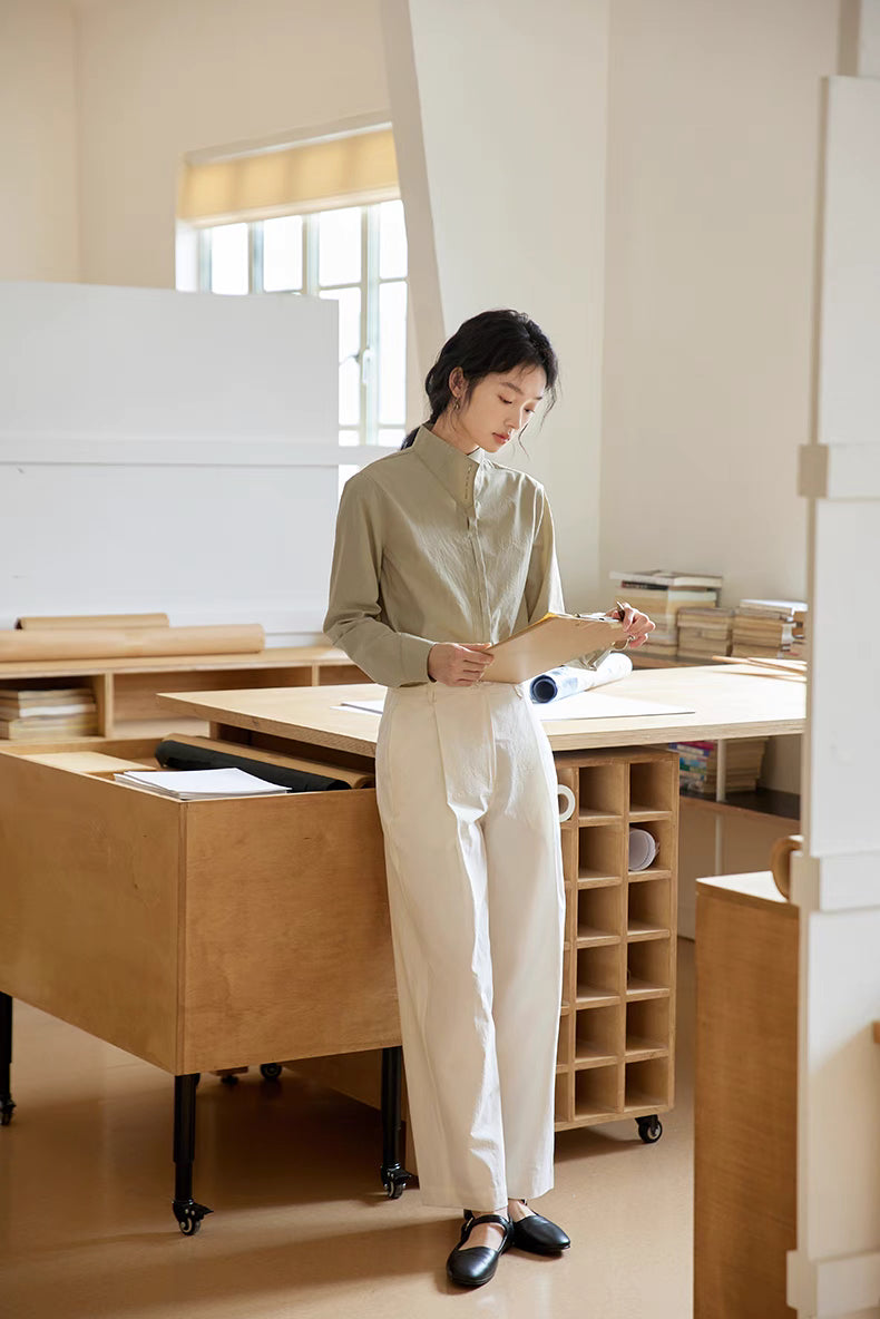 Full-body view of Teal stand-collar shirt styled with light trousers in a bright office environment, highlighting elegant structure and versatile daily wear