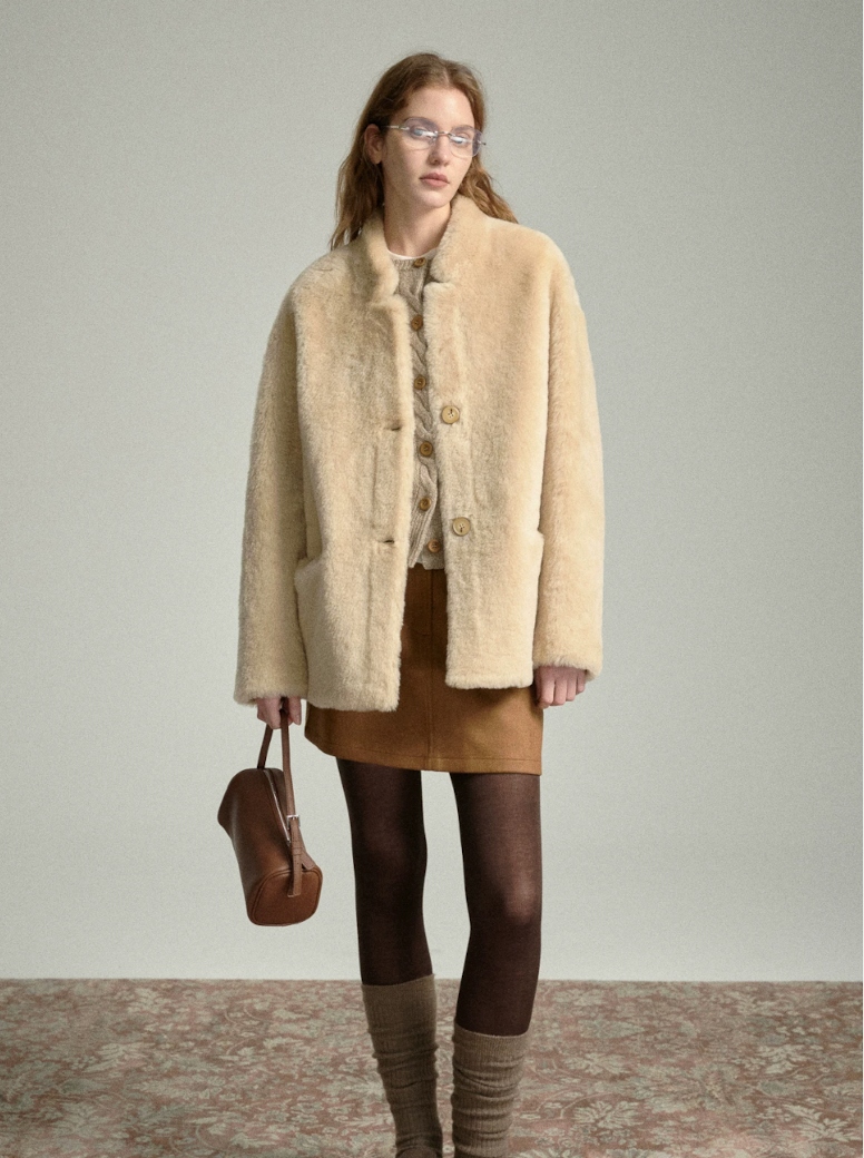 Full-length view of oat sheepskin jacket with suede mini skirt, tights and slouch socks