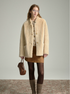 Full-length view of oat sheepskin jacket with suede mini skirt, tights and slouch socks