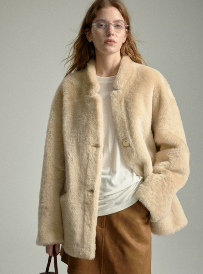 Oat merino sheepskin jacket worn open over a white tee and brown suede skirt