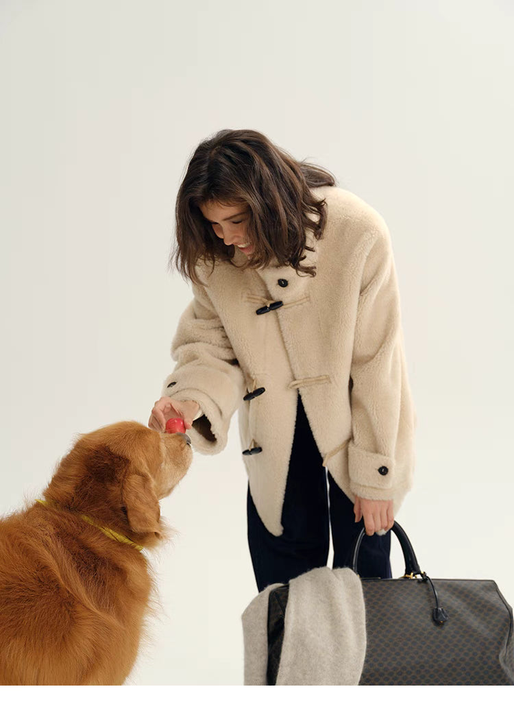 Model wearing Plush Toggle Coat in warm apricot bending to interact with dog, highlighting toggle closure, oversized sleeves, and cozy plush fabric