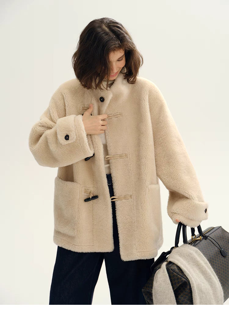 Angled front view of Plush Toggle Coat in warm apricot styled with handbag, showcasing toggle closures, patch pockets, and cozy mid-length design