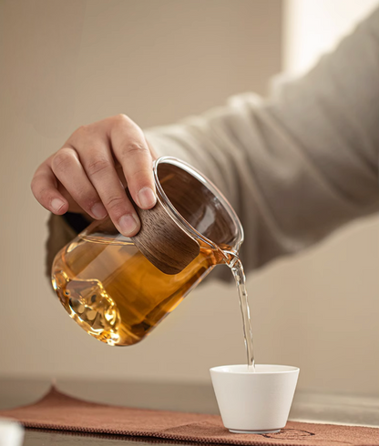 Glass teapot from white portable outdoor travel tea set pouring tea into ceramic cup