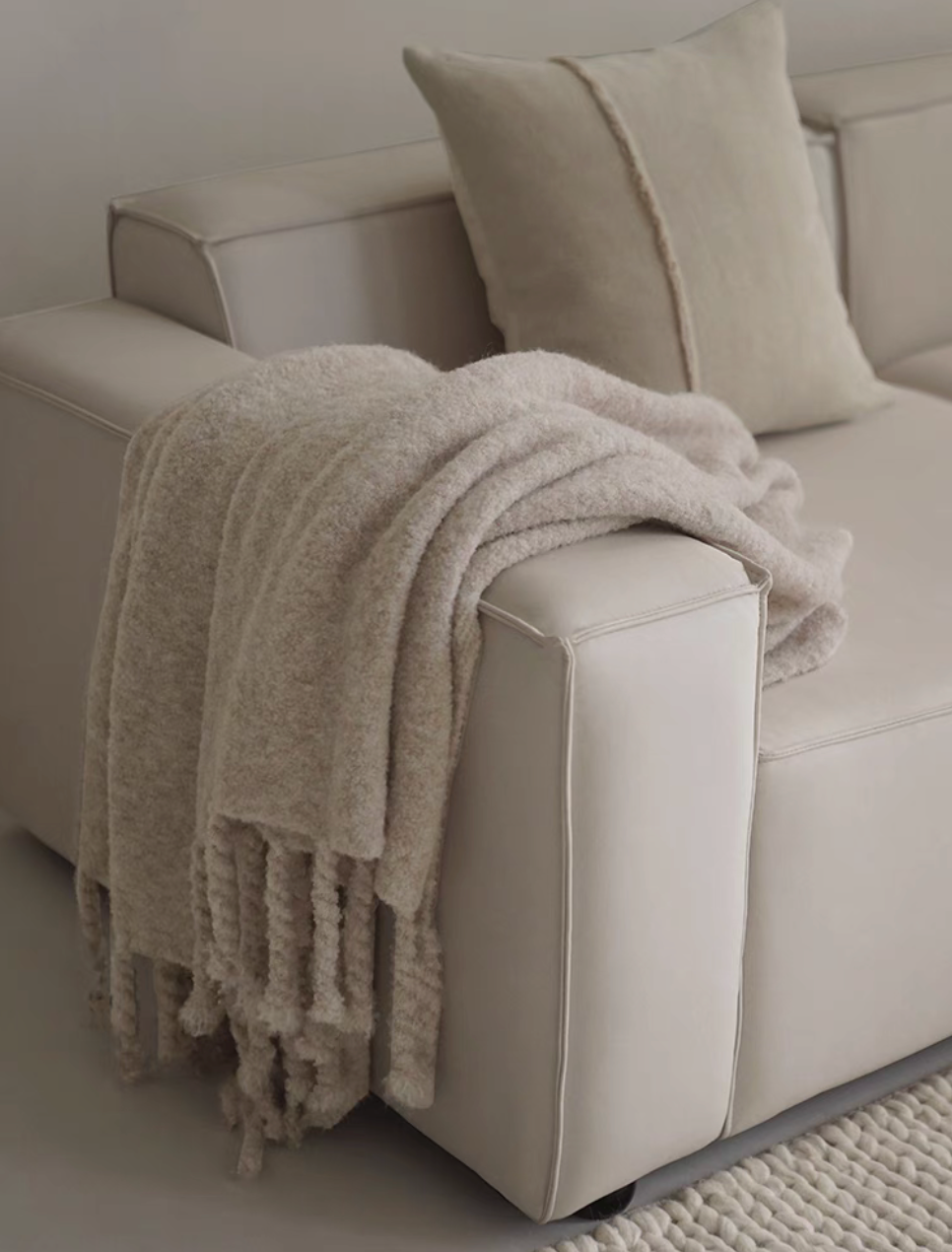 Gray pure wool throw blanket folded over the arm of a beige sofa with matching neutral cushion