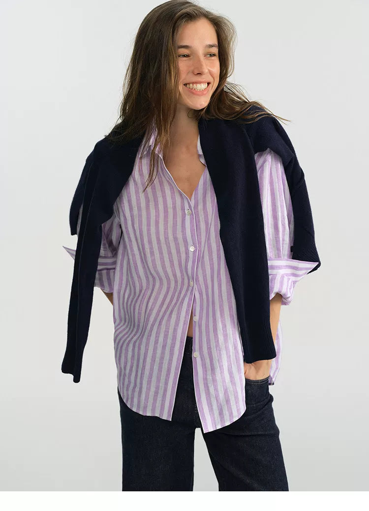 Woman smiling wearing purple stripe linen shirt with navy cardigan draped on shoulders