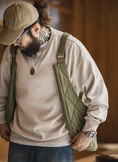 Model wearing olive green 2-in-1 quilted vest bag over beige sweater street style.