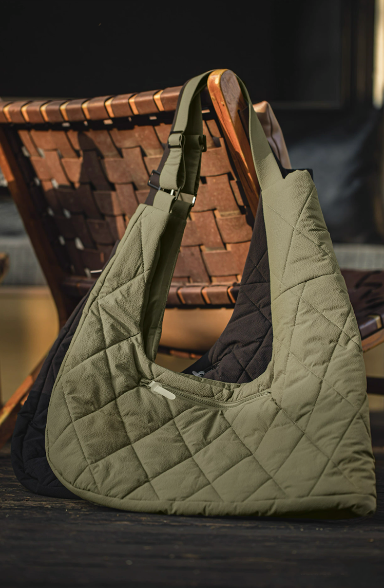 Olive and black convertible vest bags displayed together on chair in natural light.