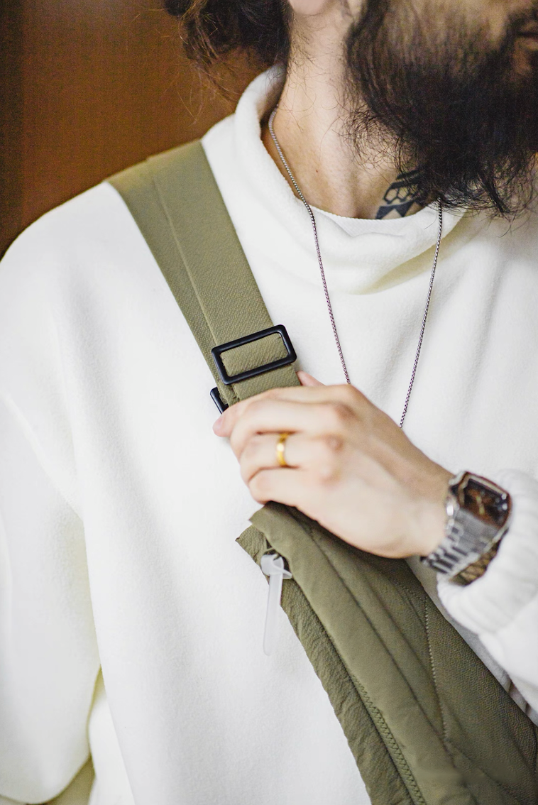 Close-up of strap and buckle detail on olive quilted convertible vest bag.