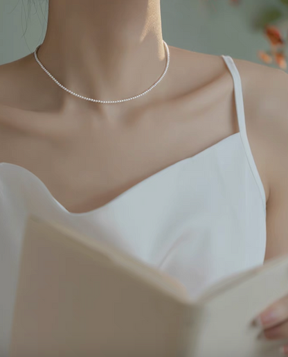 Model wearing Radiant Round Pearl Necklace in natural color while holding a book