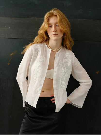 Woman wearing ivory embroidered ramie cardigan shirt with black satin skirt, front view