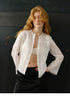 Woman wearing ivory embroidered ramie cardigan shirt with black satin skirt, front view