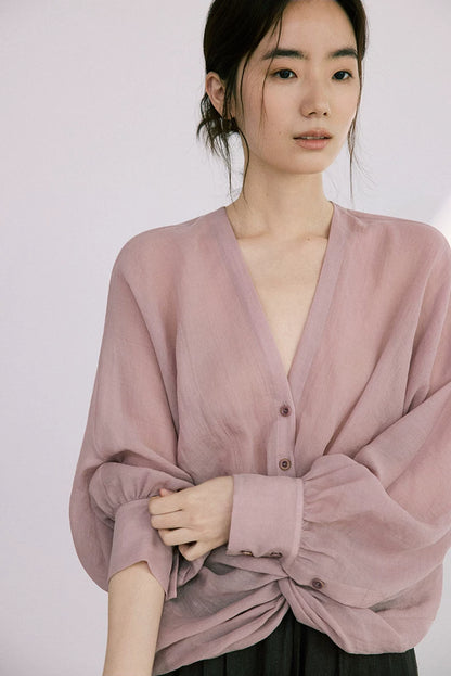 Close-up of dusty rose ramie-Tencel blouse showing twist-knot hem and V-neck detail
