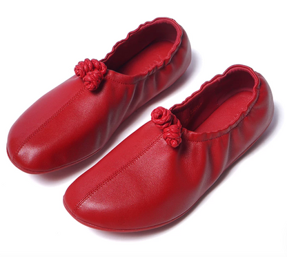 Pair of red sheepskin ballet flats with braided leather knots and gathered elastic topline, front angle view