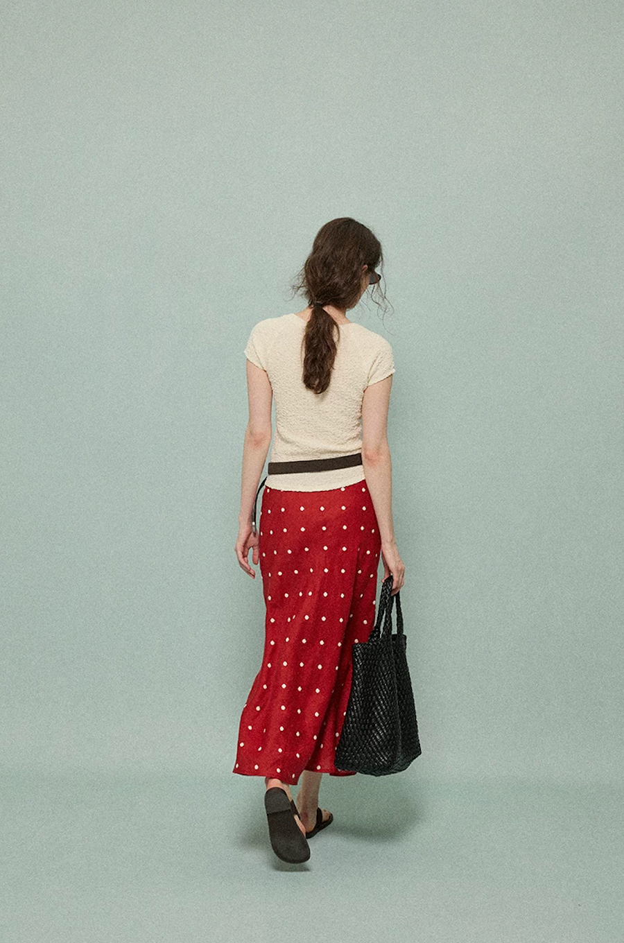 Back view of a red linen polka dot midi skirt falling to the lower calf