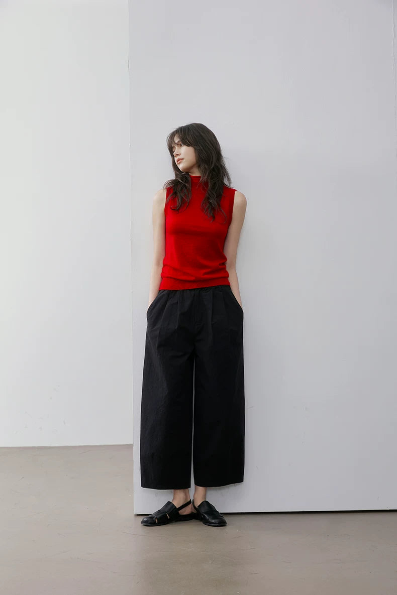 Full-length view of model leaning against wall in Red sleeveless wool knit top