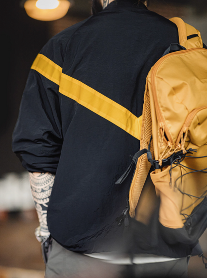 Back view of Black Reflective V-Stripe Tactical Zip Jacket worn with a backpack showing the reflective V-stripe design across the back