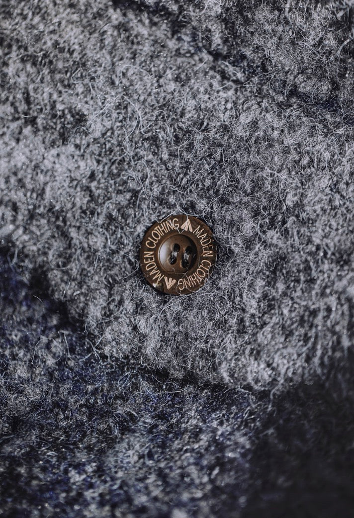 Detail of brown button on navy gray boucle wool fabric.