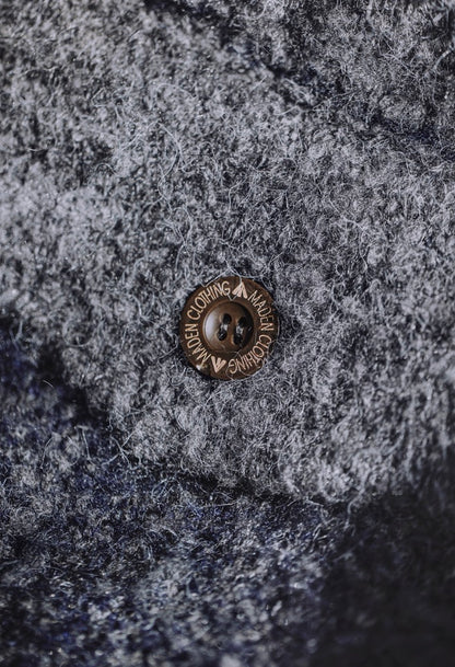 Detail of brown button on navy gray boucle wool fabric.