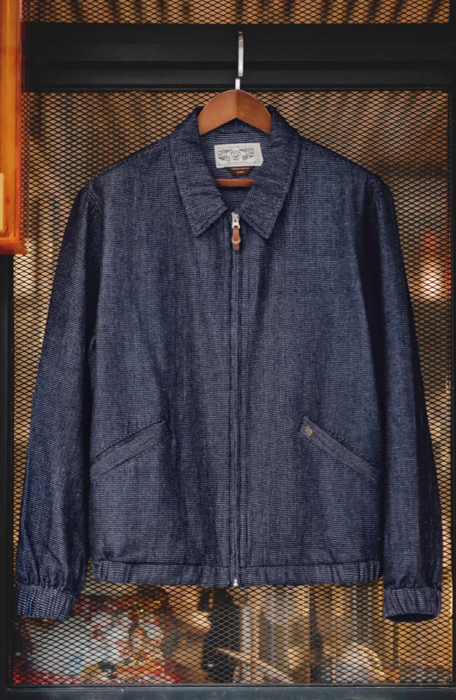 Denim coach jacket displayed on hanger against mesh background