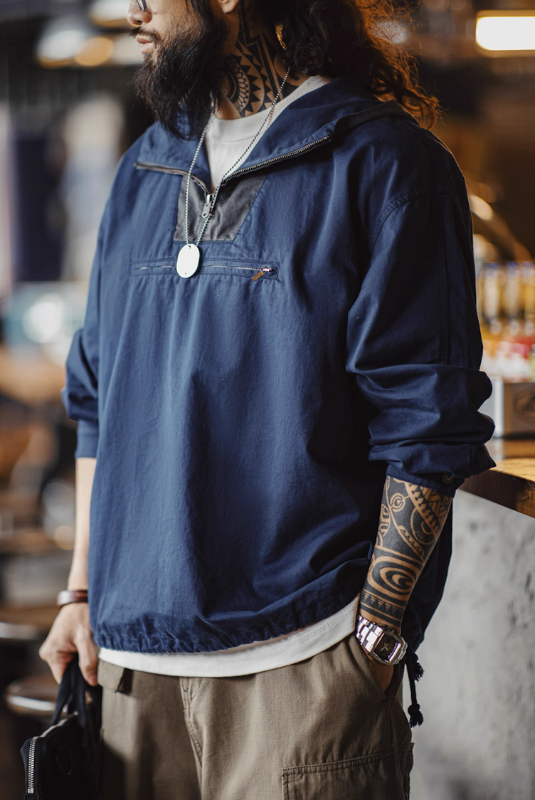 Model in navy two-tone cotton anorak standing indoors, casual urban look.