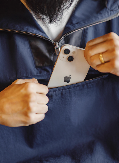 Model placing phone into front zip chest pocket of navy cotton anorak.