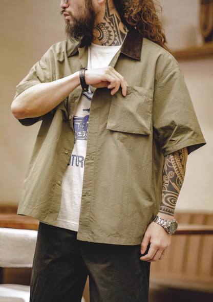 Man wearing khaki green retro waterproof utility shirt adjusting chest pocket showing textured fabric and utility design