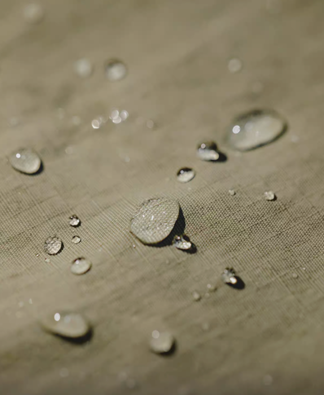 Close-up of khaki green retro waterproof utility shirt fabric with water droplets demonstrating waterproof performance