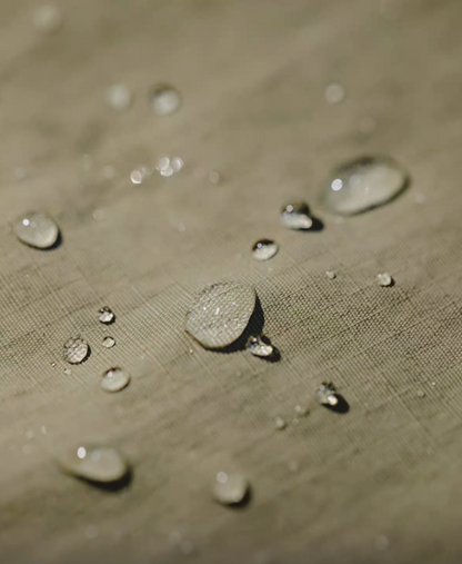 Close-up of khaki green retro waterproof utility shirt fabric with water droplets demonstrating waterproof performance