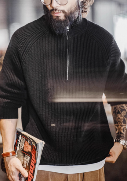 Man wearing Ridge Half-Zip Pullover Sweater in Charcoal Black holding magazine highlighting ribbed knit fabric structured collar and casual modern styling
