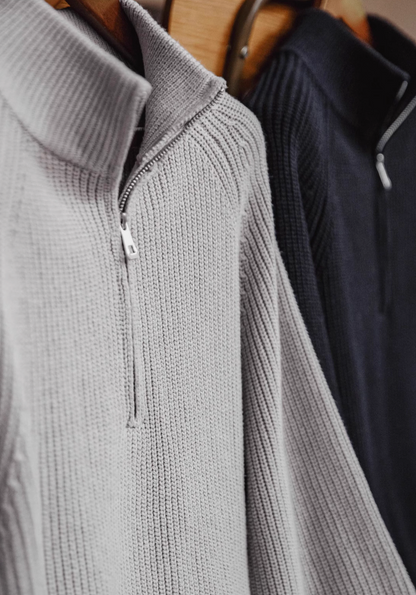 Ridge Half-Zip Pullover Sweater in Smoky Gray and Charcoal Black hanging on rack showcasing ribbed knit texture half-zip neckline and structured spread collar
