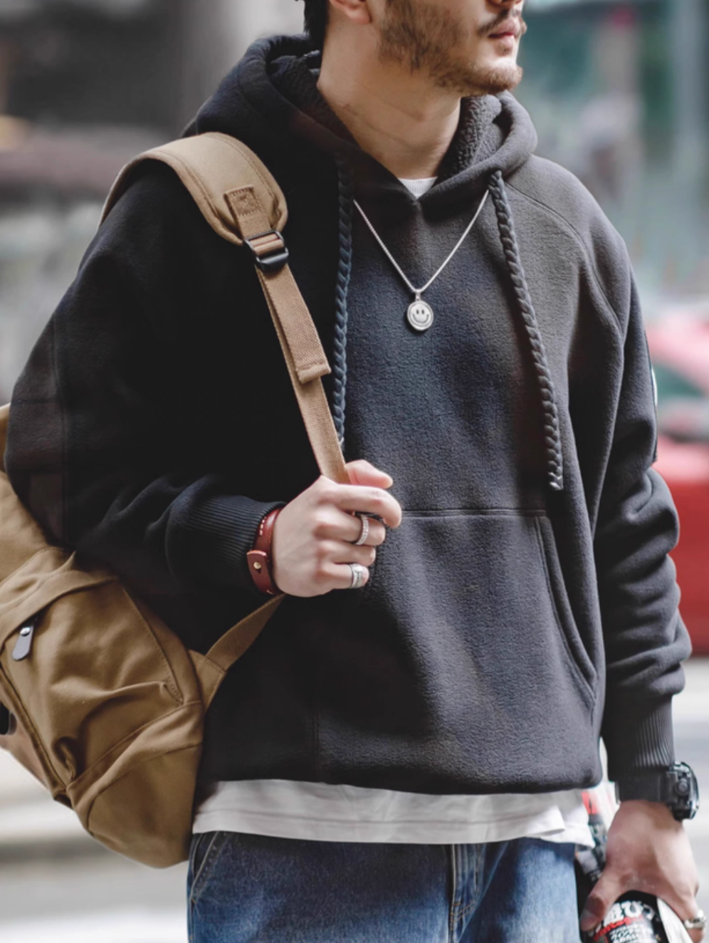 RidgeLine Fleece Hoodie in black worn with backpack featuring braided drawstrings, kangaroo pocket, and soft fleece texture for everyday streetwear