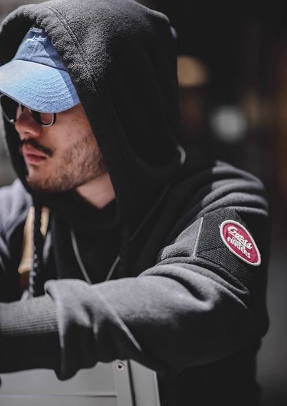 Close-up of RidgeLine Fleece Hoodie in black with hood up highlighting textured sleeve Velcro patch and soft fleece fabric