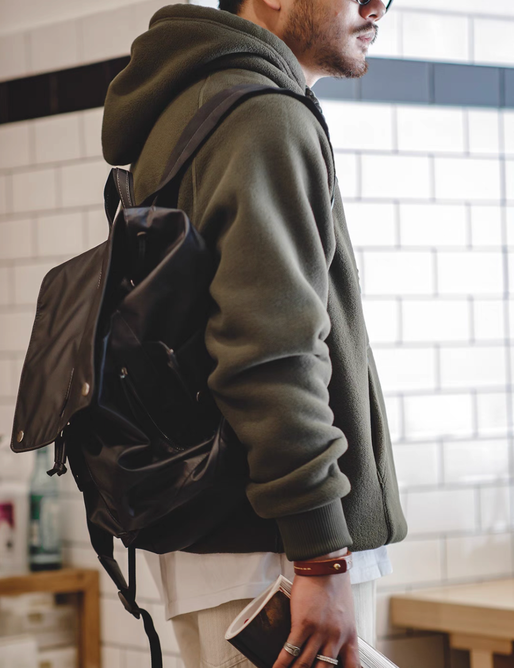 Side view of RidgeLine Fleece Hoodie in olive green styled with backpack highlighting relaxed fit and durable fleece construction