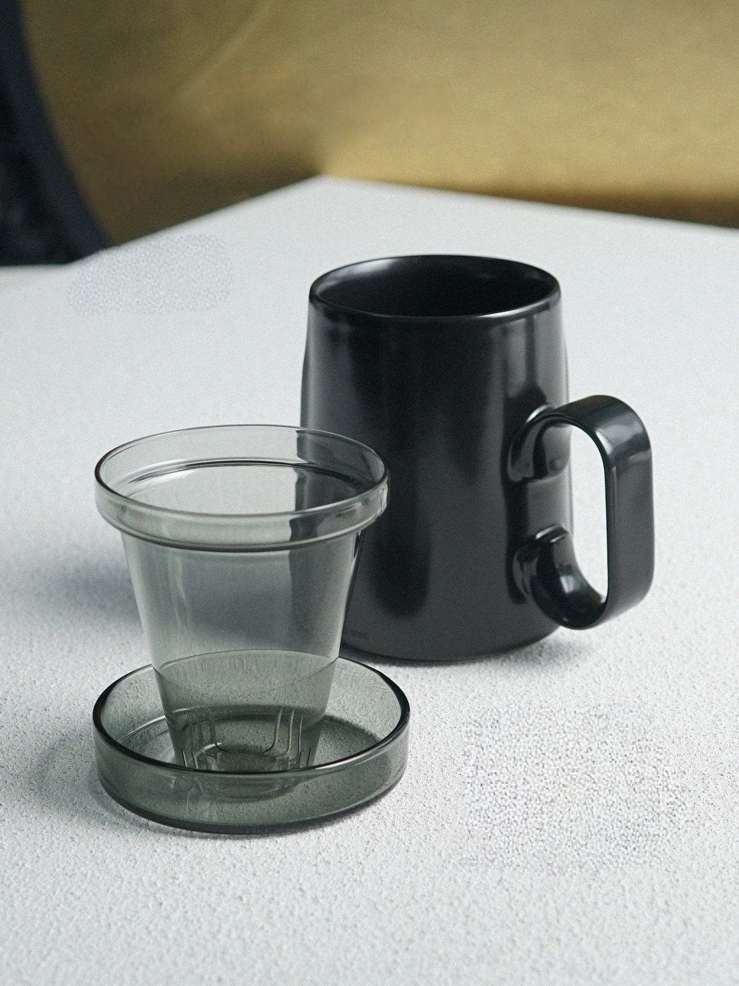 Black ring-handle ceramic tea mug with glass infuser and lid placed together, front view showing complete tea brewing set