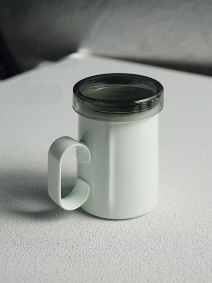 Light Green ring-handle ceramic tea mug with lid, front view showing minimalist shape and translucent lid design