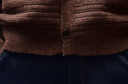 Close-up of bottom hem and button detail on men’s ripple knit cardigan