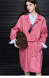 Rose Pink oversized cotton trench coat belted at the waist, showing the fly front and buckled lower tab