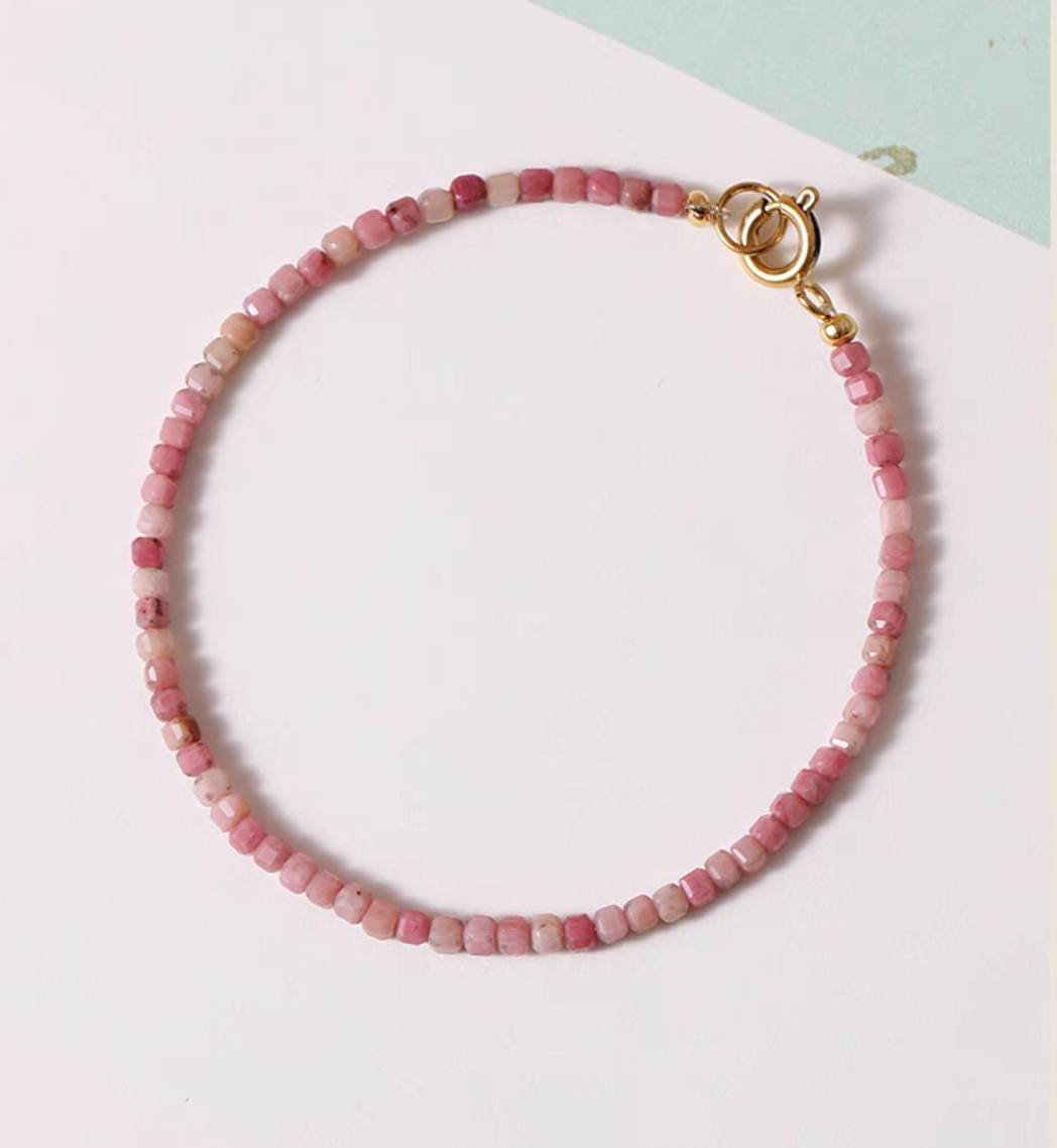 Top view of rose rhodonite bracelet arranged in a full circle showing faceted pink beads and gold clasp closure detail