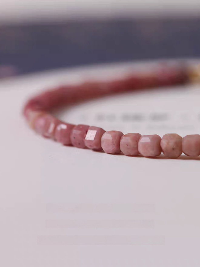 Close-up of faceted rhodonite beads highlighting natural pink variations and polished gemstone texture
