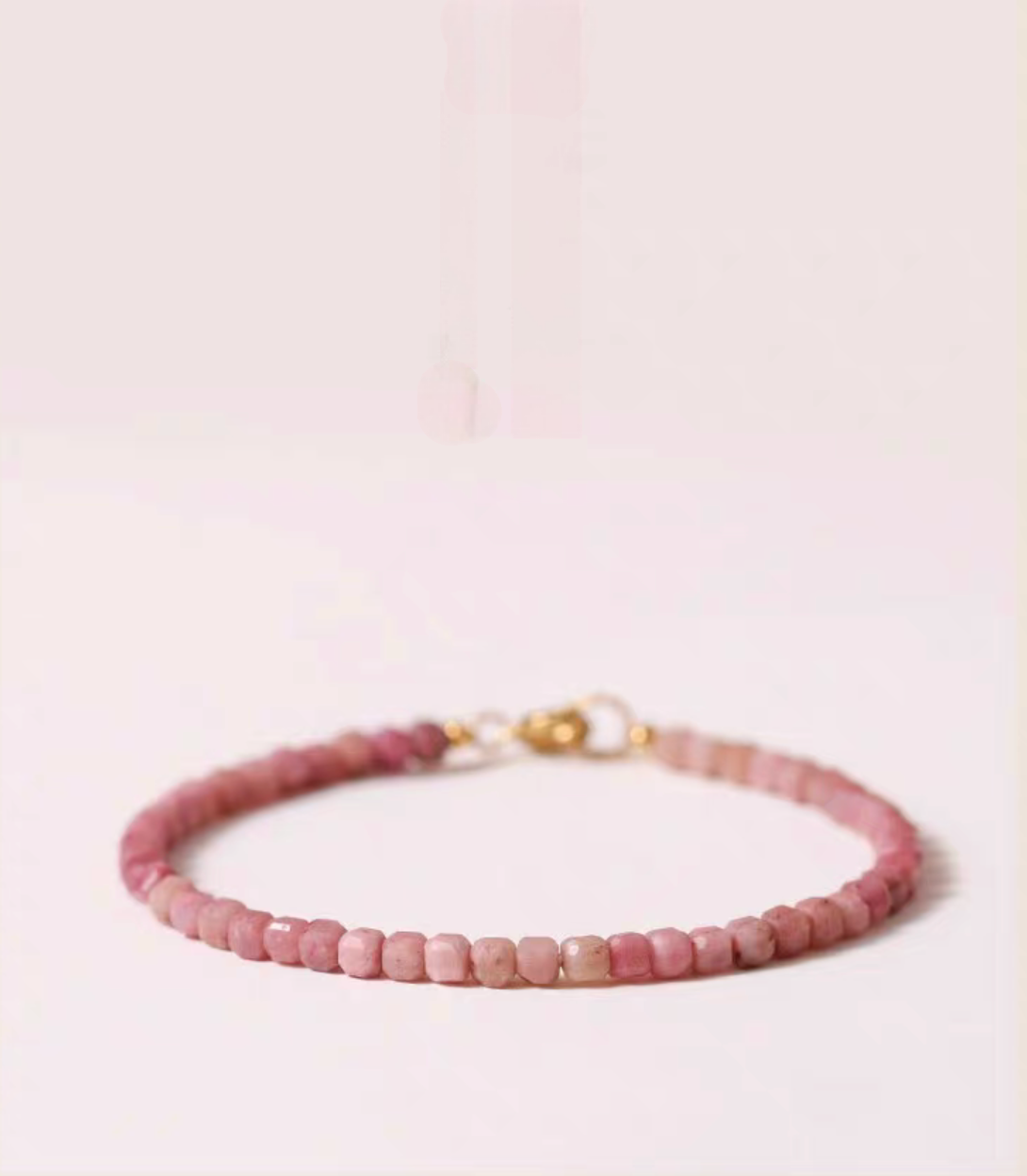 Rose rhodonite delicate bracelet in soft pink tones displayed flat with evenly arranged natural stone beads and gold clasp detail