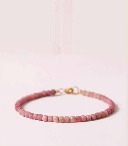 Rose rhodonite delicate bracelet in soft pink tones displayed flat with evenly arranged natural stone beads and gold clasp detail