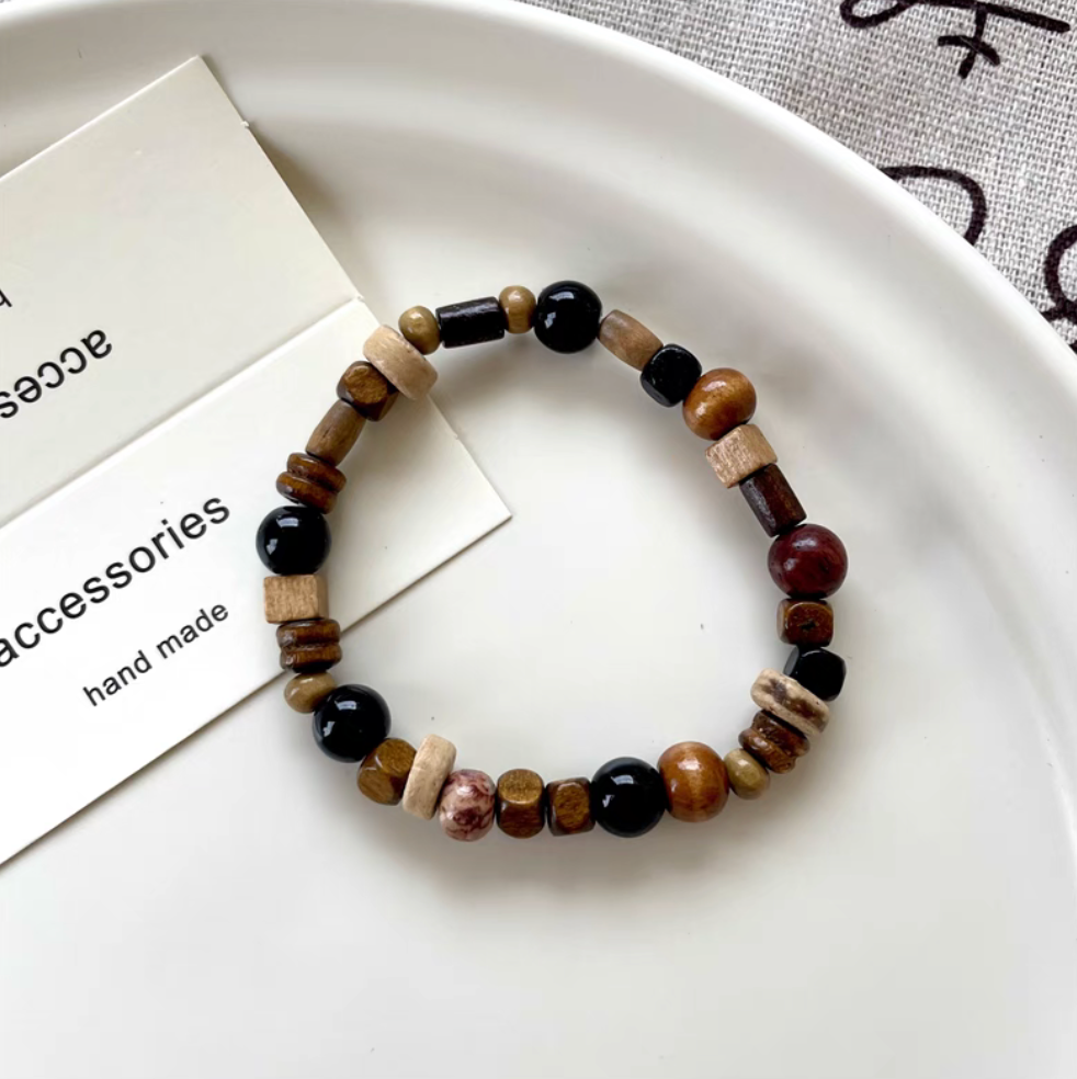 rustic wooden elements bracelet with mixed wood beads and dark accents displayed on white plate with card