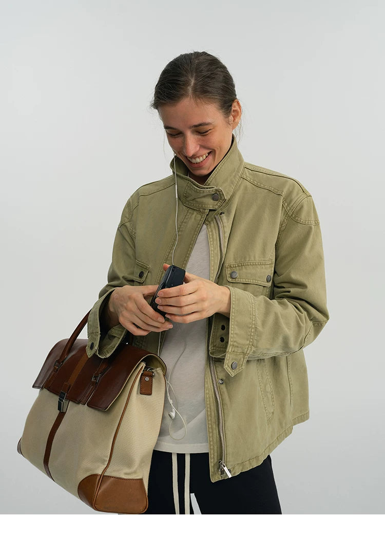 Close-up of a sage green field jacket showing the stand collar snap tab and snap cuffs