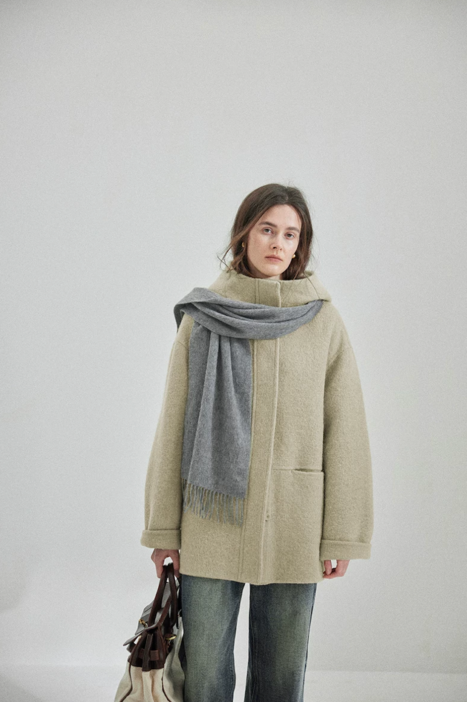 Sage hooded wool coat buttoned to the stand collar, with welt side pocket and rolled cuffs