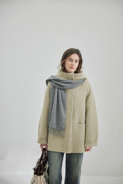 Sage hooded wool coat buttoned to the stand collar, with welt side pocket and rolled cuffs