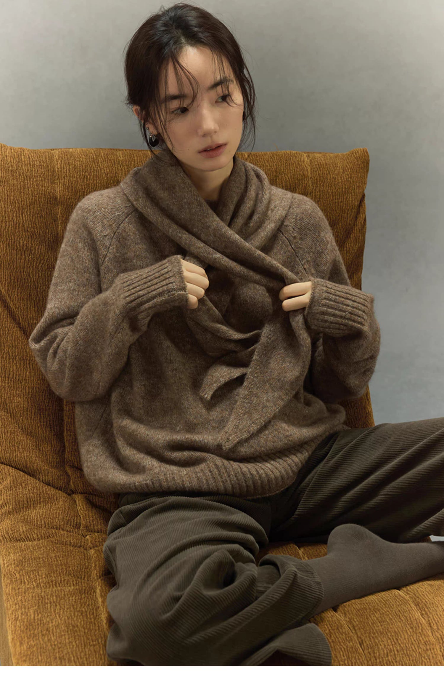 woman seated with light coffee brown scarf draped over sweater