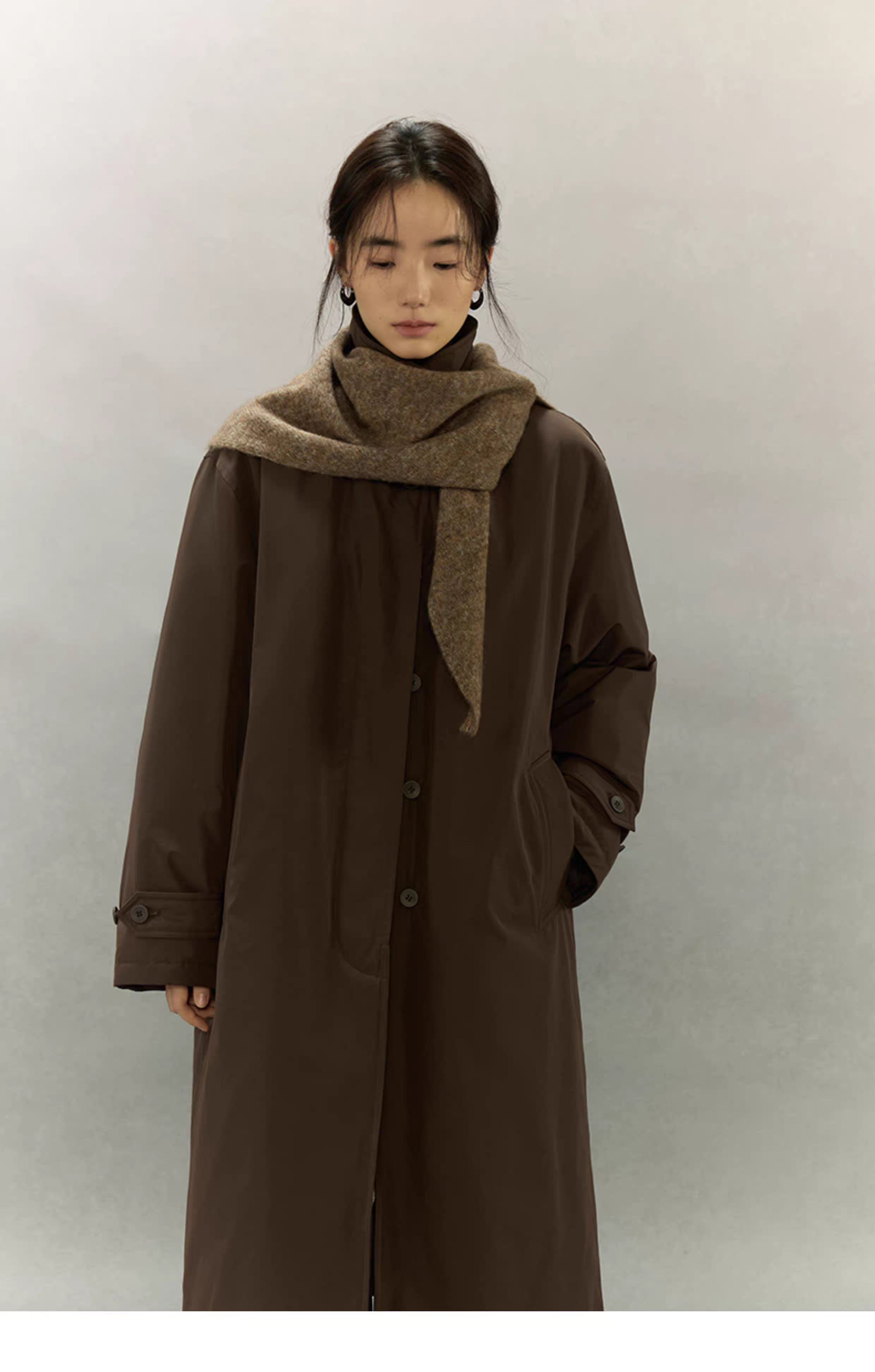 woman wearing oversized dark coat with light coffee brown scarf wrapped around neck