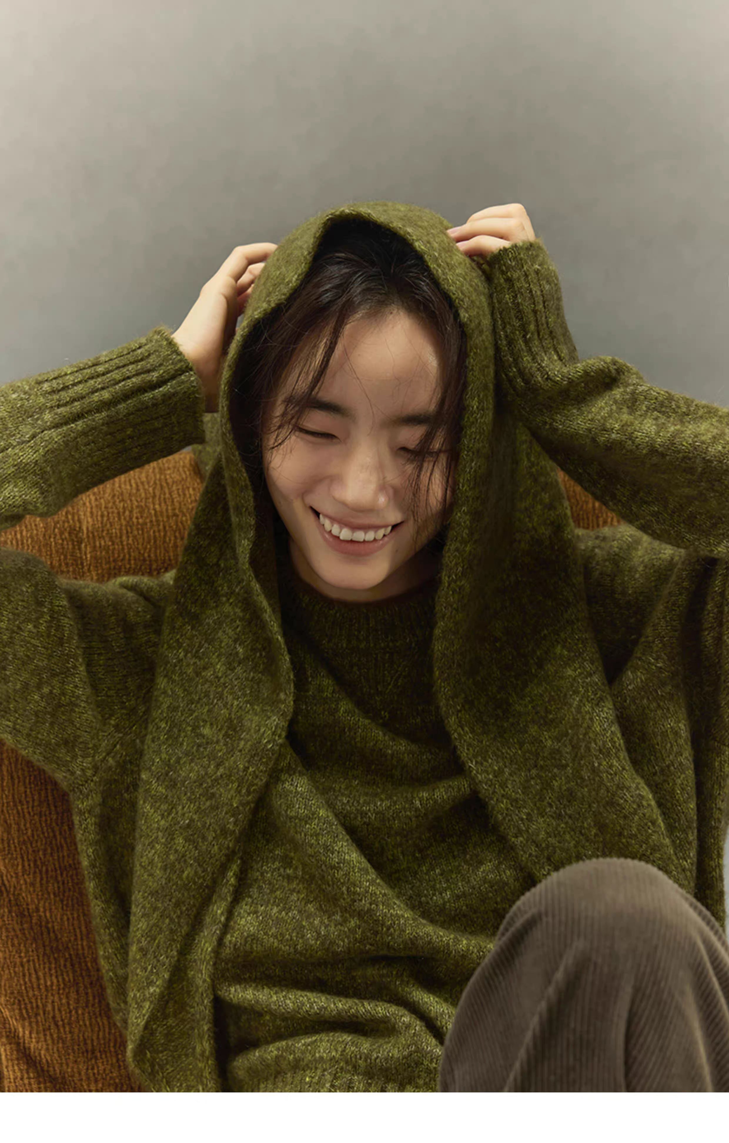 woman smiling with moss green cashmere wool scarf draped over head and shoulders